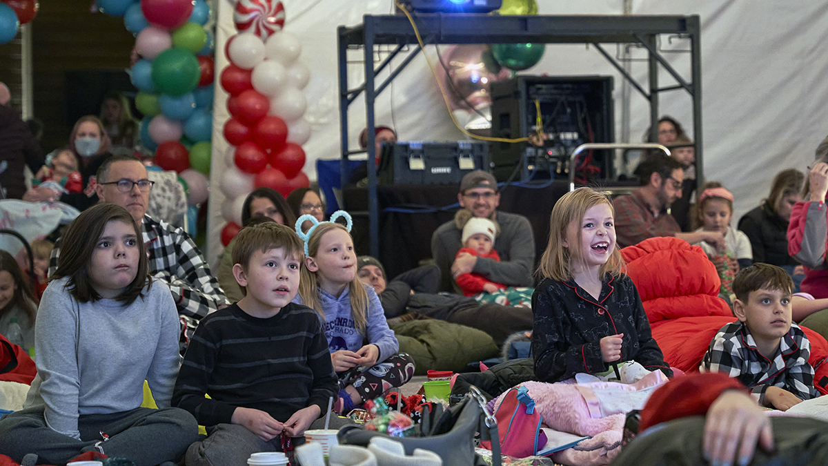 A group of kids gathered around watching a movie.